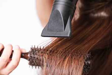 Beautiful young woman is using a hair dryer.