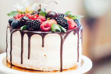 Wedding cake with strawberries, blackberries, blueberries, cherries on table