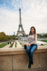 Beautiful lady sist on border against of eiffel tower. Lady smile and have fun