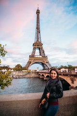 Fototapeta na wymiar Beautiful young girl in front of eiffel tower. Girl is smiling and rejoising. autumn photo