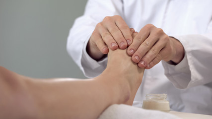 Masseur applying massaging cream to patients leg, relaxing procedures, health