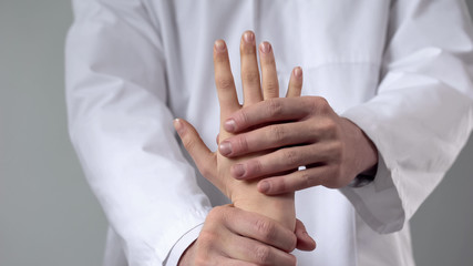 Doctor moving patient wrist, first aid in clinic, assessing severity of injury
