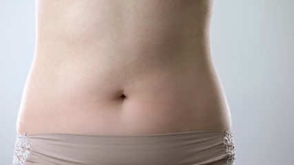 Fototapeta na wymiar Young ladys flat belly closeup, healthy nutrition and beautiful slim body