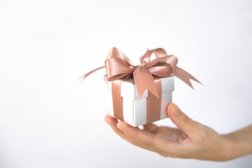A female hand holding or giving a gift box in an isolated white background.