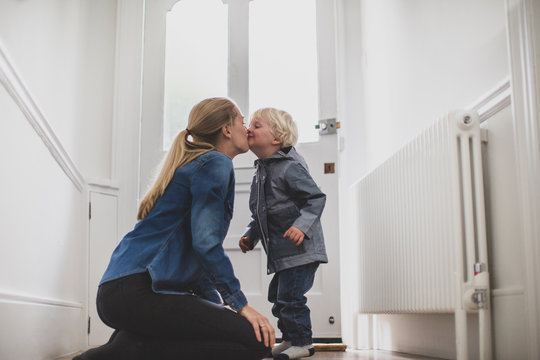 Mother and child kissing goodbye at home