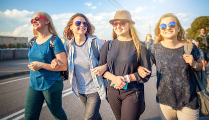 Group of happy smiling carefree young stylish girl go for a walk together on the background of the city, millenial concept, youth and students, tourism and holidays