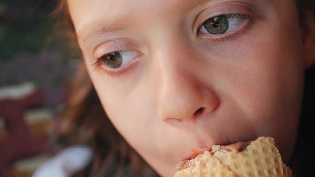 Baby mouth bites chocolate ice cream close-up.