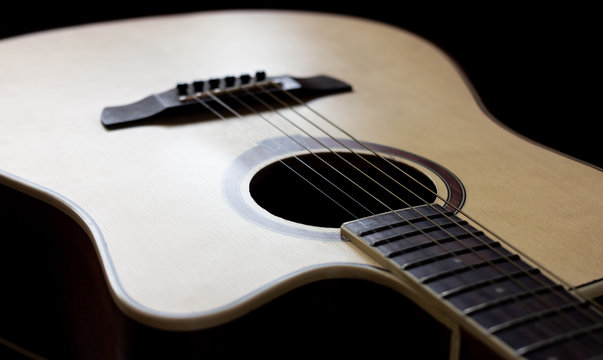 Wooden guitar with lighting on the body to show texture of guitar