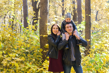 Family, fall, people concept - mixed race young family walking in park on in autumn day