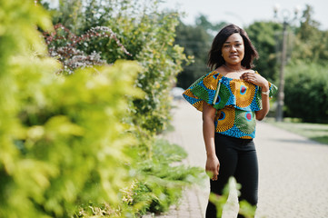 African american girl in coloured shirt and black pants posed outdoor. Fashionable black woman.