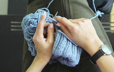 Knitting. Female hands with knitting needles. Top view. Close-up.