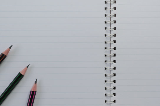 Wirebound Notebook Open with Lined Paper and Pencils.