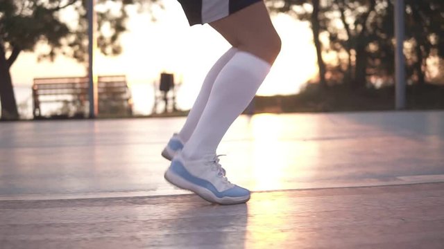 Close up shot of female basketball player legs doing dribbling exersice very quickly without ball, training outdoors on the local court
