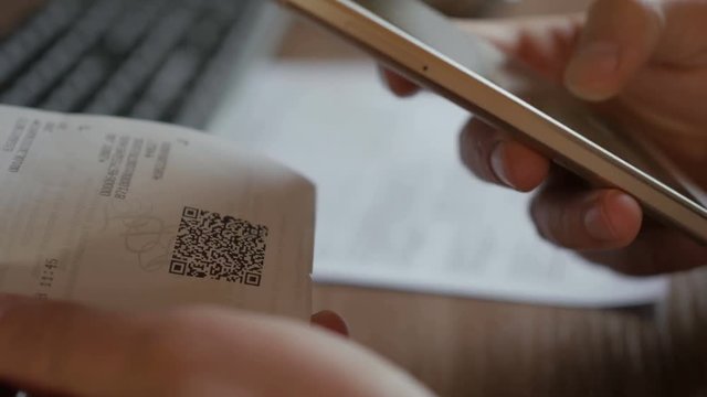 A man scans the QR code on a check from a supermarket.