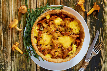 Traditional homemade swedish pie - quiche with chanterelle mushrooms, cheese and fresh rosemary decorated with vintage silver knife and fork on the rustic kitchen table. Top view