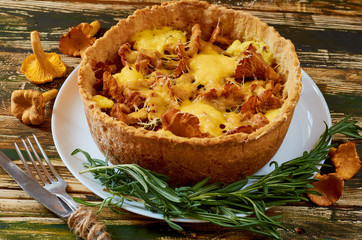 Traditional homemade swedish pie - chanterelle mushrooms and cheese quiche with fresh rosemary decorated with vintage silver knife and fork on the wooden kitchen table. Close up view