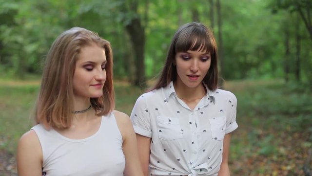 Enamored same-sex couple walking in the park, kissing, happy.