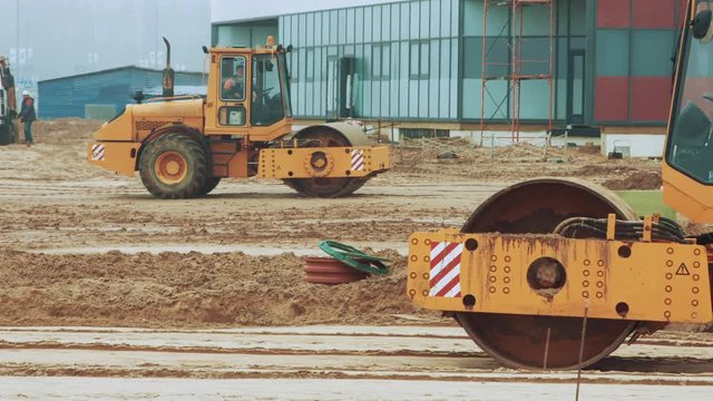 Yellow road roller working on road construction site. Industrial heavy machinery at asphalt pavement work. Vibratory soil compactor machine working