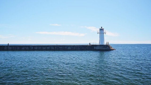 Backlit lighthouse at the end of a stone pier in lake Vattern outside Hjo in Sweden.