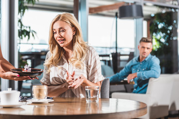 surprised blonde woman looking at dessert with flower in restaurant