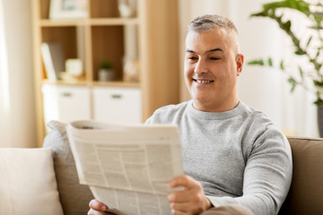 Fototapeta premium leisure, information, people and mass media concept - man reading newspaper at home
