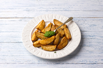 Baked potatoes with kale pesto sauce on a light blue background, selective focus. Delicious vegan homemade food