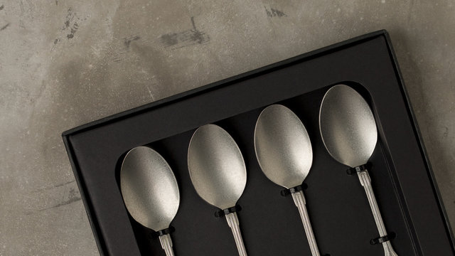 Top view of silver collection of tablespoons teaspoons in a black box on a gray concrete background