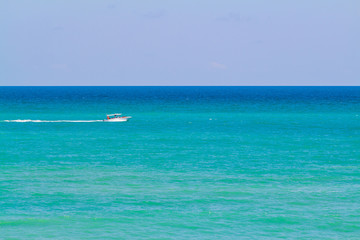 The smooth sea and the small boat with people. Clearly sky in sunshine day.