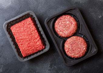 Plastic tray with raw minced homemade meat beef burgers with spices and herbs. Top view.