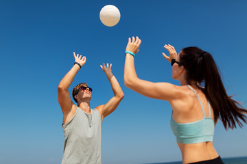 fitness, sport and lifestyle concept - happy couple with ball playing volleyball on summer beach