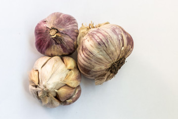 three dry garlic heads on a white background