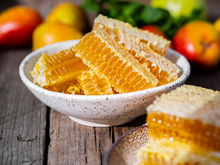 honey in honeycomb, close-up, on white ceramic plate, on wooden rustic table, side view, sunlight in sunny day.