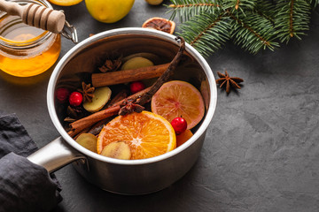 Mulled wine hot drink with citrus, apple and spices in aluminum casserole and Fir branch on background.