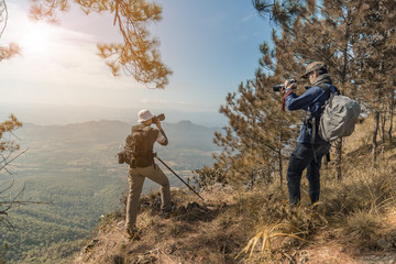 Photographer with camera in hand on top of mountain.