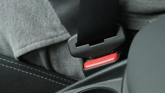 Passenger in car connects 3-point seat  belt on bracket 4K video