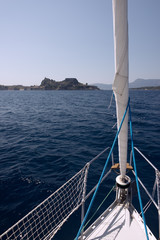 Naklejka na ściany i meble Sailing boat reaching an island in the Mediterranean sea