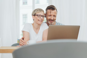 Middle aged couple sat using laptop together