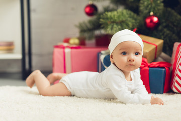 adorable little baby lying on floor with christmas gifts
