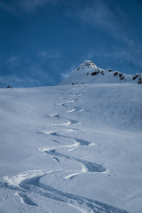 Skispur im Tiefschnee unter blauem Himmel