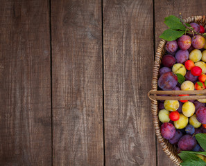 variety of plums on wooden surface