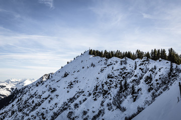 Gipfelkreuz im Winter unter blauem Himmel mit Schnee