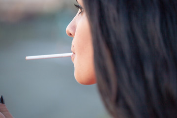 Portrait of a young beautiful girl who smokes a cigarette. Close-up portrait.