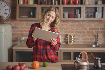 Woman in a red shirt with a digital tablet in the kitchen