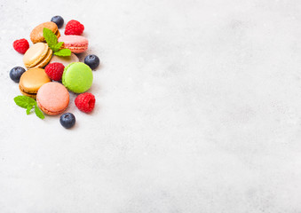 Dessert cake macaron or macaroon with raspberry and blueberry on stone kitchen table background . Top view. Space for text