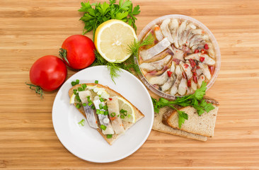 Open sandwich with pickled herring and ingredients for its preparation