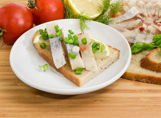 Open sandwich with pickled herring and ingredients for its preparation