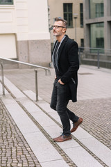 Stylish middle-aged man walking through the city