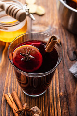 Hot mulled wine with spices, citrus and honey on woodern background. Copy space.