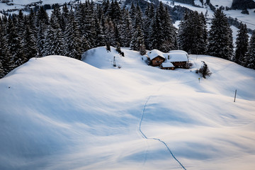 Verschneite Winterlandschaft mit Hütte und Skispur 