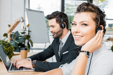 side view of smiling call center operators at workplace in office